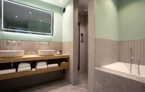 a bathroom with two sinks and a tub at Relais & Chateaux Hotel Landgoed Het Roode Koper in Ermelo