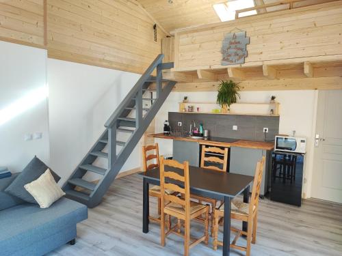 a kitchen and living room with a table and a staircase at Petit Coin de Bonheur studio Neuf et lumineux à 5mins du Centre-ville in La Mure