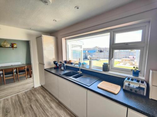 a kitchen with a sink and a window at Seaside bungalow 5 mins walk to beach and town in Bude