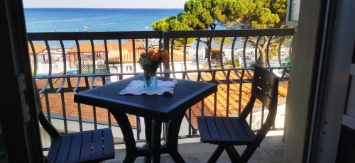 une table bleue avec un vase de fleurs sur un balcon dans l'établissement L'oasi di copanello, à Copanello