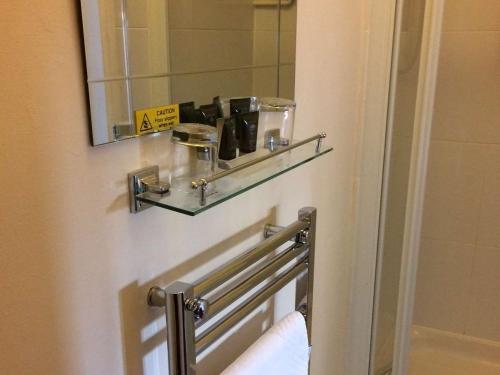 a bathroom with a mirror and a shelf on a door at Rose and Crown in Burwash