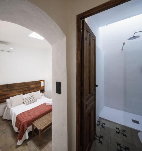 a bedroom with a bed and a walk in shower at Casablanca Vejer Baño Termal in Vejer de la Frontera