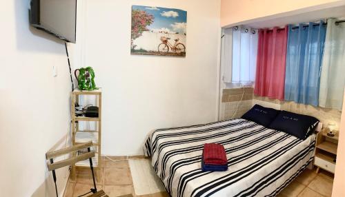 ein kleines Schlafzimmer mit einem Bett mit gestreifter Decke in der Unterkunft Dotan's Boutique Apartments - By The Beach! in Tel Aviv