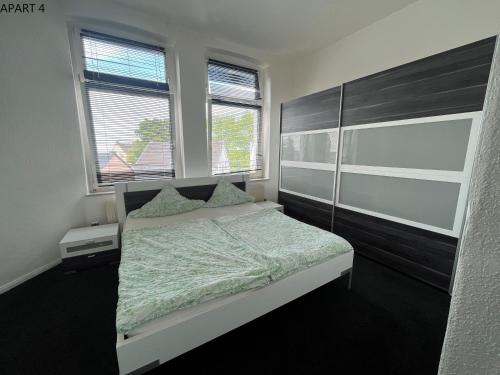 ein Schlafzimmer mit einem Bett und zwei Fenstern in der Unterkunft Apartment in Solingen Ohligs in Solingen