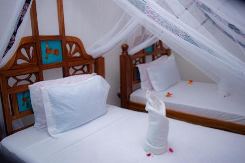 two beds in a room with white sheets and curtains at Jabali Bungalows Lodge in Paje