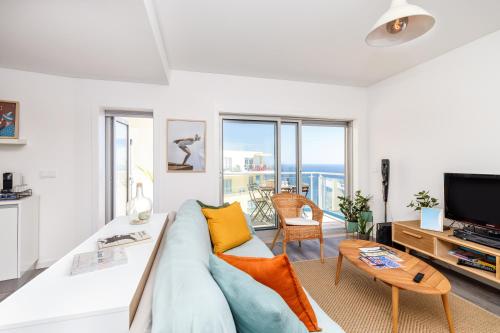 a living room with a couch and a tv at Sesimbra Sunshine Cliffs in Sesimbra