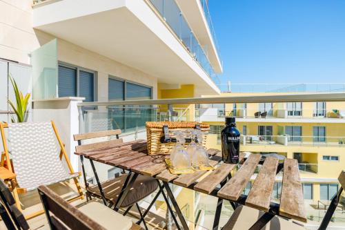 - une table en bois avec une bouteille de vin sur le balcon dans l'établissement Sesimbra Sunshine Cliffs, à Sesimbra