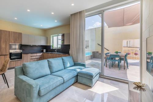 a living room with a blue couch and a kitchen at Celestina Farmhouse in Xagħra