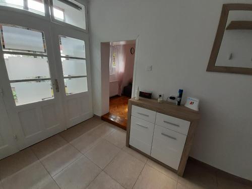 a kitchen with white cabinets and a door and a tile floor at Apartman Stevan in Pirot