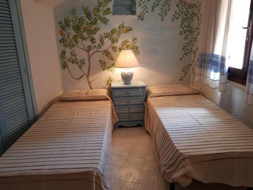 2 camas en un dormitorio con una lámpara en un tocador en Porto Cervo Prestige en Porto Cervo