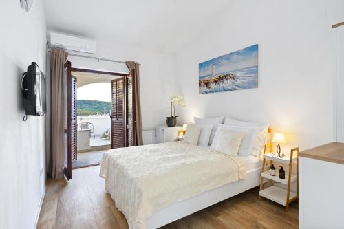 een witte slaapkamer met een bed en een balkon bij Black Pearl Tisno in Tisno