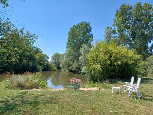two white chairs sitting in front of a pond at la ferme aux kangourous in Donzy
