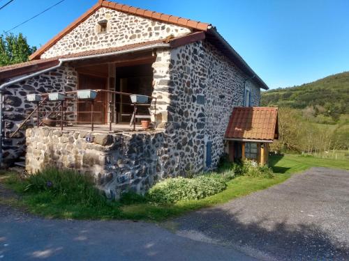 une maison en pierre avec une terrasse couverte et un mur en pierre dans l'établissement Studio 45m2, à la campagne, à 15 mns du Puy en Velay, à Lantriac