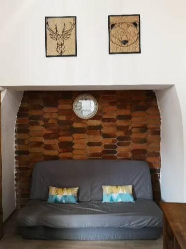 - un canapé dans une chambre avec un mur en briques dans l'établissement CAUTERETS Appart centre ville et calme idéal pr rando, ski et cure, à Cauterets