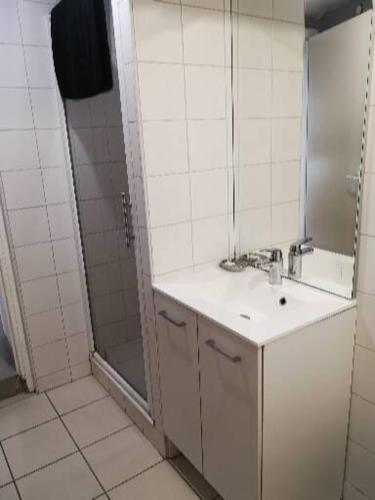 une salle de bain blanche avec un lavabo et une douche dans l'établissement CAUTERETS Appart centre ville et calme idéal pr rando, ski et cure, à Cauterets