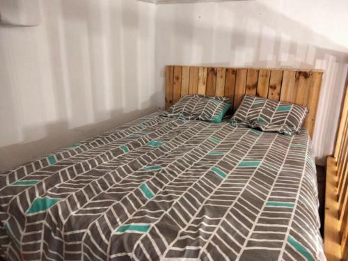 een slaapkamer met een bed met een houten hoofdeinde en kussens bij CAUTERETS Appart centre ville et calme idéal pr rando, ski et cure in Cauterets