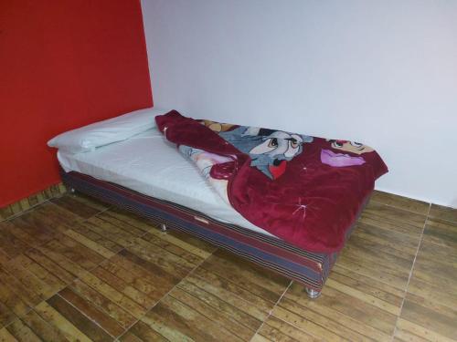 Una cama pequeña con una manta roja. en Dany ka, en Naj‘ al Maḩaţţah
