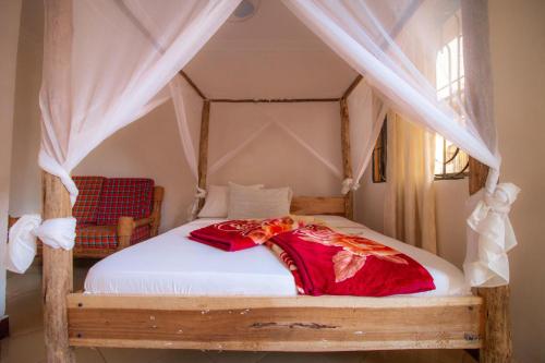 1 dormitorio con cama con dosel y cortinas blancas en The Better Inn en Moshi