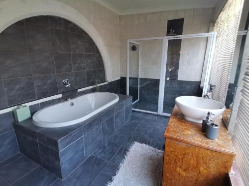 a large bathroom with a tub and a sink at Die Blom in Krugersdorp