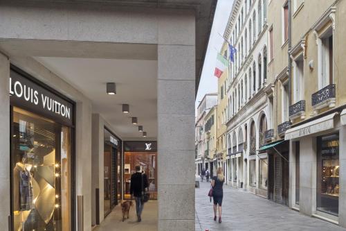 a couple of people walking down a street with buildings at Hotel Firenze in Venice