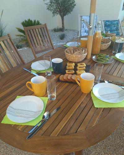 une table en bois avec des assiettes, des tasses et de la nourriture dans l'établissement Les Chemins d'Ambre et Thaïs, à La Regrippière