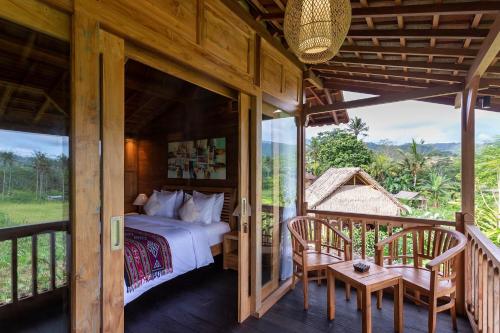 - une chambre avec un lit et deux chaises sur une terrasse couverte dans l'établissement Kubu Sakian Villa, à Silebeng