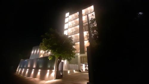 un bâtiment éclairé avec un arbre devant lui dans l'établissement Apna Colombo, à Nawala