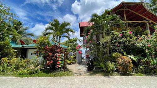 a house with a lot of flowers and palm trees at Reggae Vibes De Romblon in Agpanabat