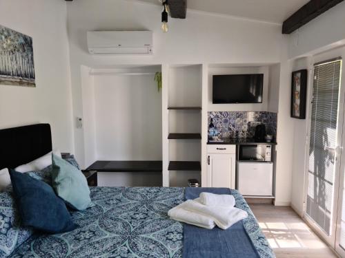 a bedroom with a bed and a tv and a kitchen at Casa das Margaridas in Caldas da Rainha
