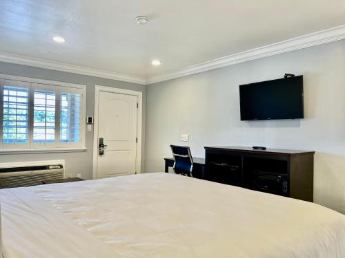 a bedroom with a bed and a desk and a flat screen tv at Aura Inn Monterey in Monterey