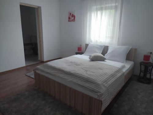 een slaapkamer met een groot bed met witte lakens en een raam bij Dumbrava Minunată in Peşteana