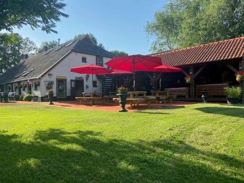 a building with picnic tables and red umbrellas at De Linde, boerderij in Drenthe voor 15 tot 30 personen in Linde