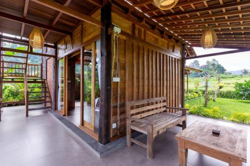 a wooden porch with a bench and a table at Kubu Sakian Villa and Restaurant Sidemen in Silebeng