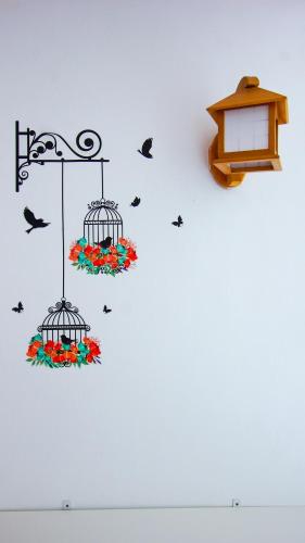 a bird cage with flowers and birds on a wall at Sakura Home in Batu Ferringhi