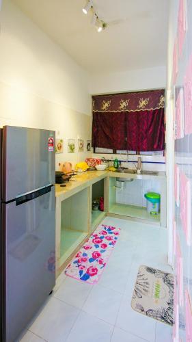 a kitchen with a refrigerator and a white tile floor at Sakura Home in Batu Ferringhi