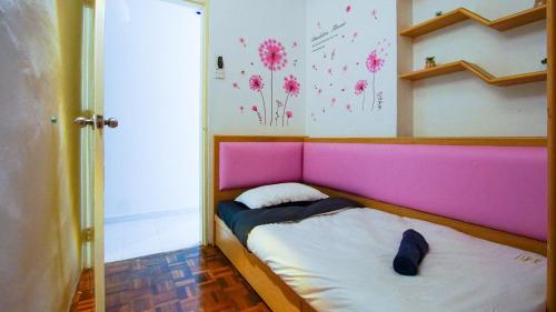 a small bed with a pink headboard in a room at Sakura Home in Batu Ferringhi