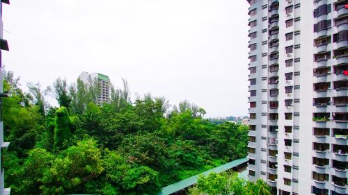 a tall white building with trees in front of it at Sakura Home in Batu Ferringhi