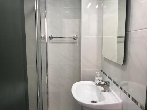 La salle de bains blanche est pourvue d'un lavabo et d'une douche. dans l'établissement Sublime Yellow Bedroom, à Lisbonne