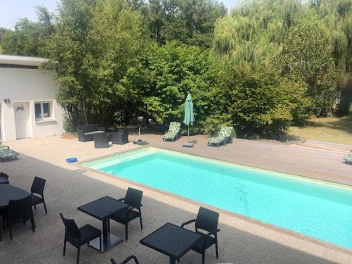 a swimming pool with tables and chairs next to at Maison Art Deco-5 suites, piscine, clim, parking in Labouheyre