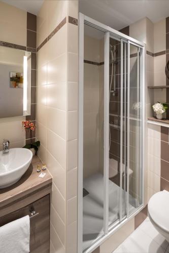 a bathroom with a shower and a sink at Hôtel Les Nations The Originals Boutique VICHY in Vichy