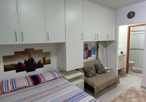 1 dormitorio con cama, sofá y armarios blancos en Apto Canção Nova - Condomínio da Fé, en Cachoeira Paulista