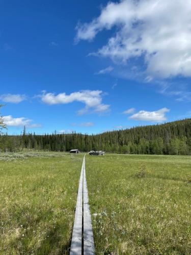 a wooden path through a field with a blue sky at Villa JoenPolku Ruka in Ruka