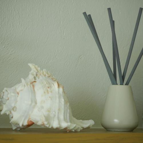 a white vase with sticks in it next to a table at Chelona Beachfront Huahin in Khao Tao
