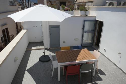 a table and chairs and an umbrella on a balcony at Casa Margherita - Guest House in Pezze di Greco