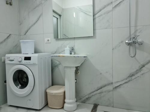 a bathroom with a washing machine and a sink at Black'n White Apartment in Vlorë