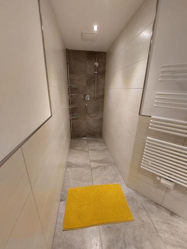 y baño con ducha y alfombra amarilla. en Ferienwohnung Julia Kröll, en Mittersill