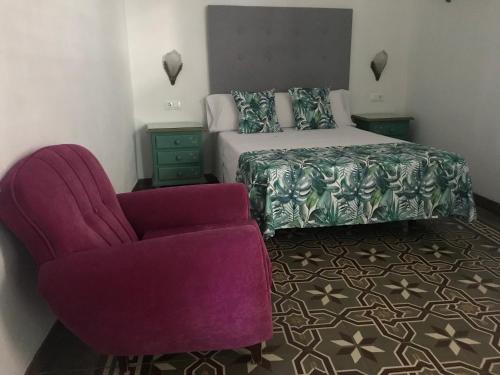 a bedroom with a purple chair and a bed at La Casa en el Centro in Écija