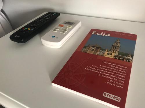 a book next to a remote control and a magazine at La Casa en el Centro in Écija