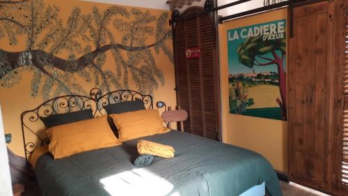 ein Schlafzimmer mit einem Bett mit einem Baumbild an der Wand in der Unterkunft La tonnelle d'Olivier in La Cadière-dʼAzur