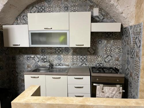 een keuken met witte kasten, een wastafel en een fornuis bij JASMINE HOUSE in Triggiano